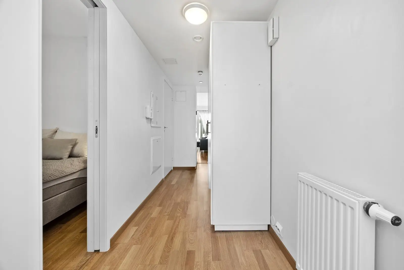 Lys og innbydende entré med trestavs eikeparkett på gulv og malte, slette veggflater.