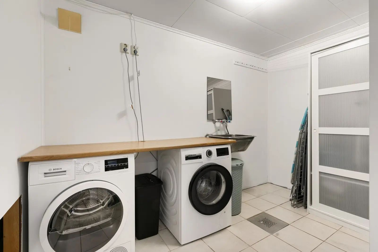 Vaskerom med flislagt gulv, utslagsvask og opplegg for vaskemaskin.