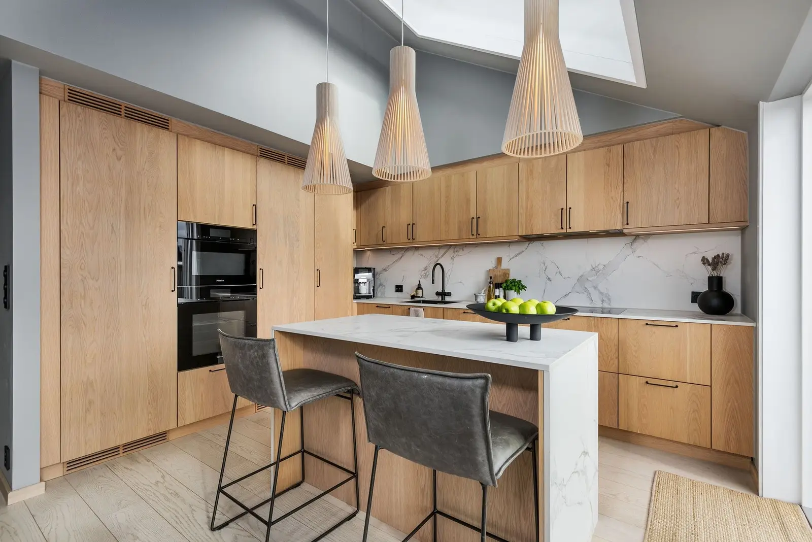 Benkeplate, vegg og kjøkkenøy er utført i Dekton - waterfall mønster på kjøkkenøy