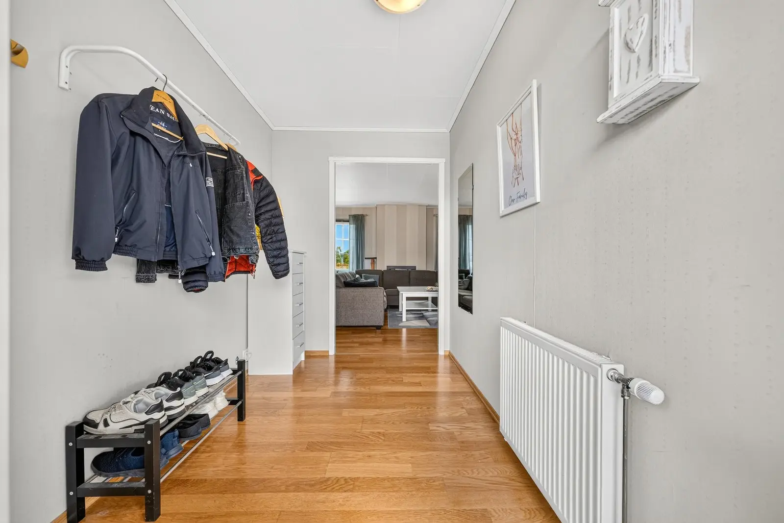 Romslig entré med parkett på gulv og lyse, tapetserte veggflater som gir et godt førsteinntrykk av boligen.