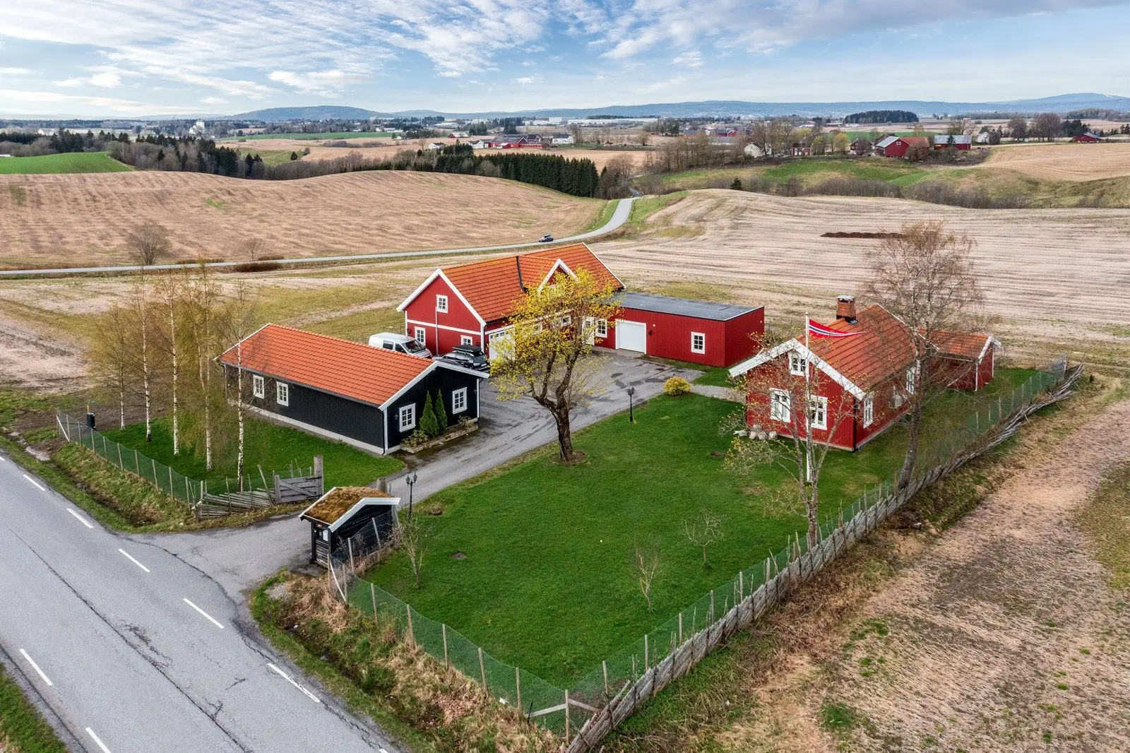Fin hage opparbeidet med plen og beplanting, samt asfaltert innkjøring og gårdsplass.