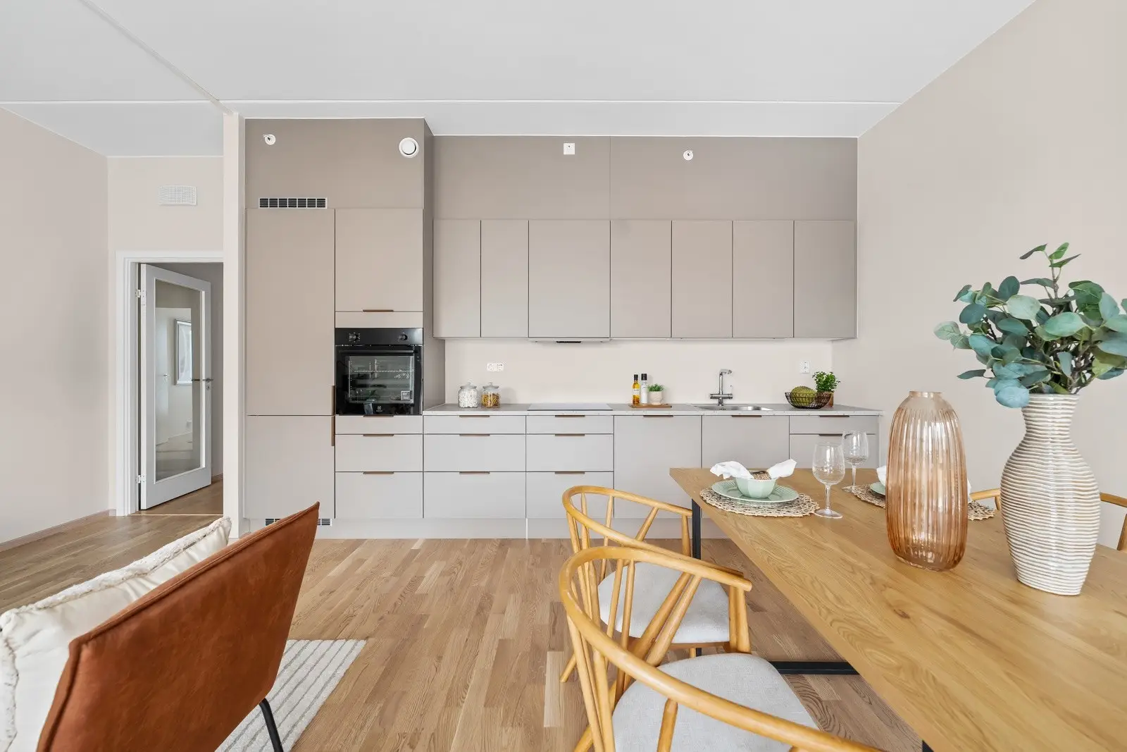 Stilrent HTH-kjøkken med beige, slette fronter og laminat benkeplate med nedfelt vaskekum. Integrerte hvitevarer medfølger.