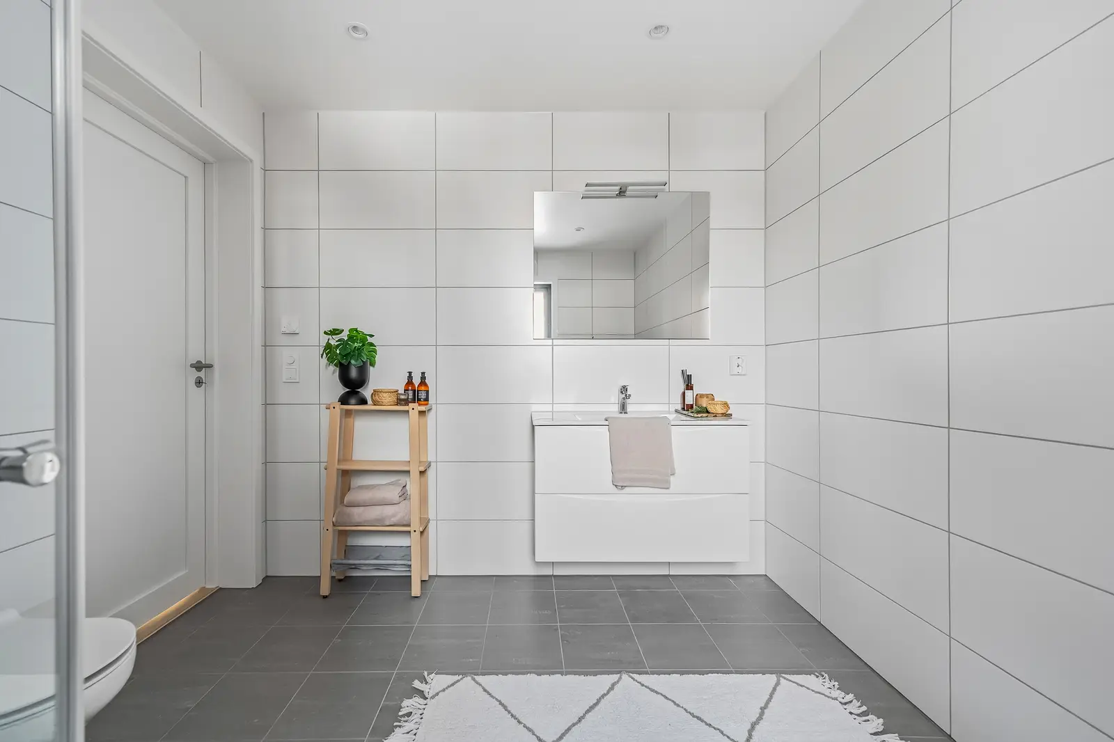 Det romslige hovedbadet ligger praktisk til i nærhet av soverommene og får en moderne og tidløs finish. Baderomsinnredningen leveres med hvi